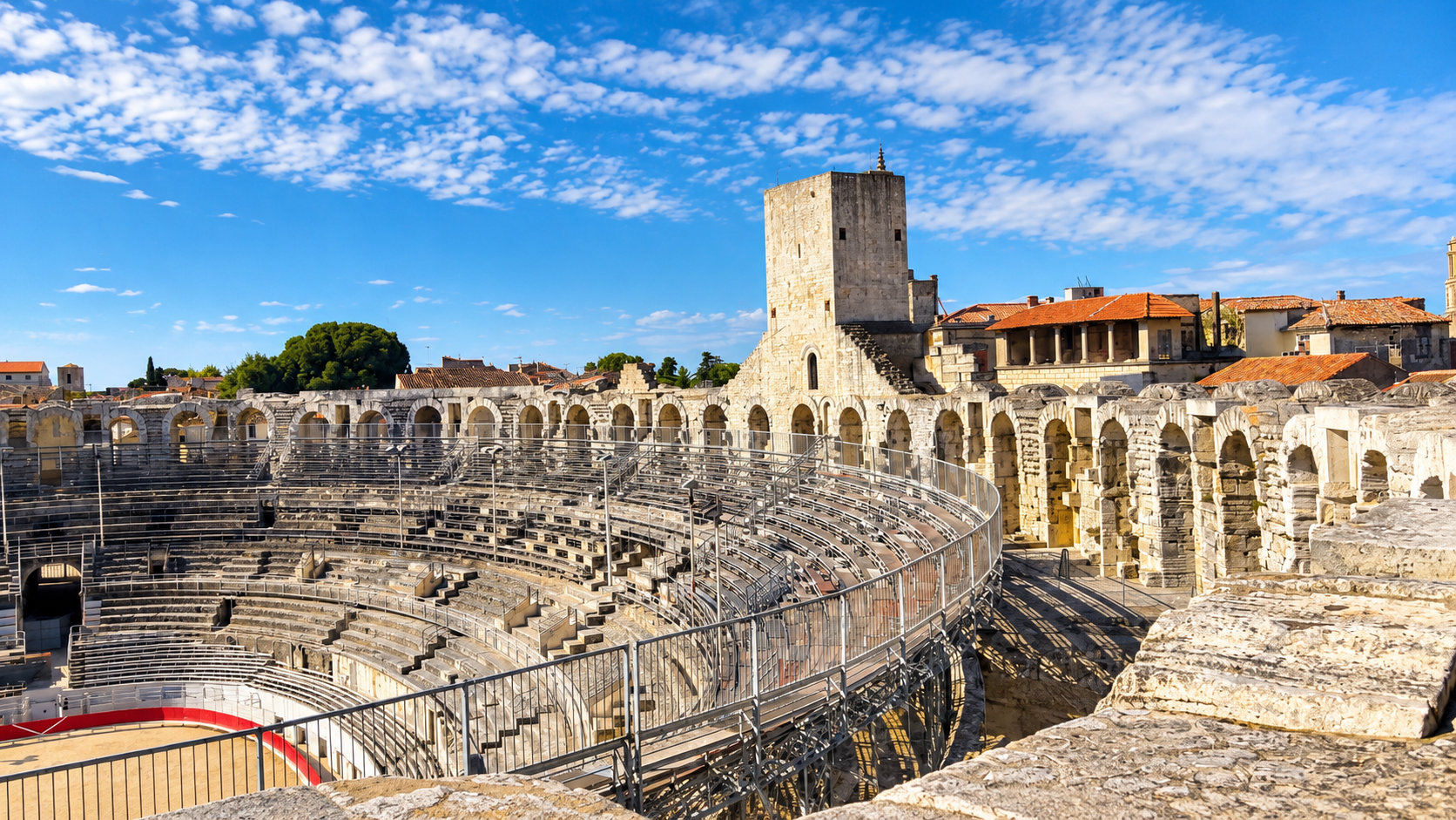 Wide view across the Roman amphitheater in Arles with stone arches and tower