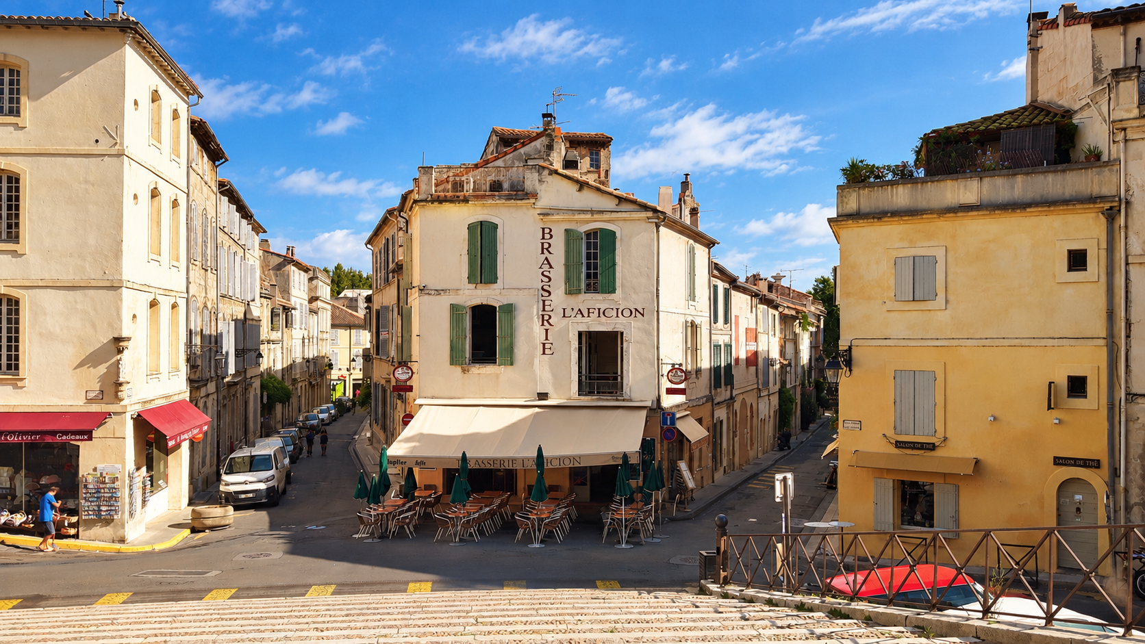 Sunlit Arles street with a brasserie and shuttered buildings